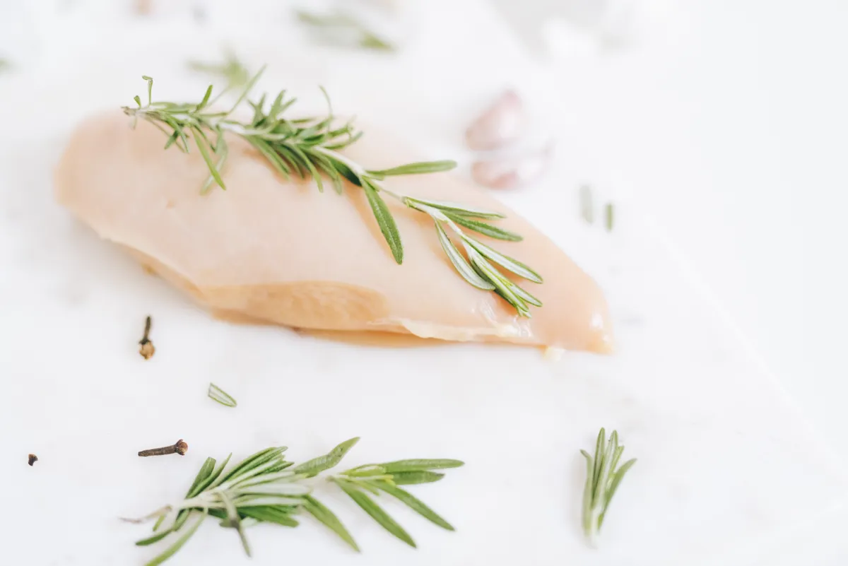 Blanc de poulet cru au romarin sur un plan de travail