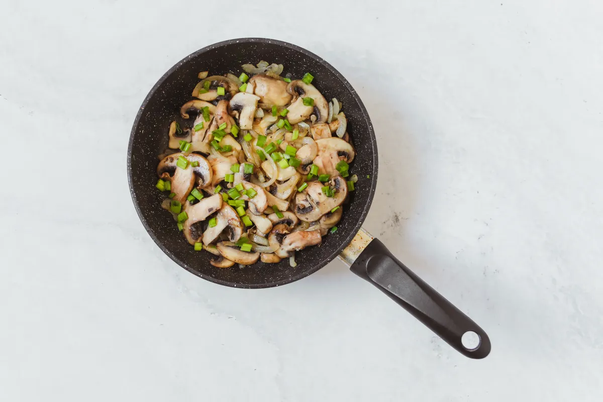 Champignons sautés aux oignons nouveaux dans une poêle